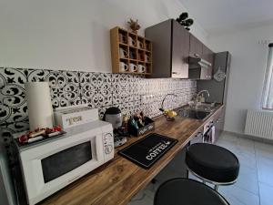 a kitchen with a microwave and a counter with stools at Vén Malom Apartman in Zalaszentgrót