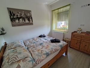 a bedroom with a bed and a dresser and a window at Vén Malom Apartman in Zalaszentgrót