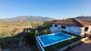 a villa with a swimming pool and mountains in the background at Chalet Venta del Aire Cortijo Terrón in Lanjarón