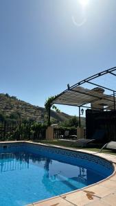 a large swimming pool with blue water at Hotel Rural Huerta del Laurel in Monachil