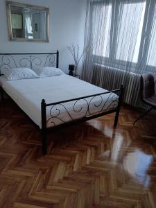 a bedroom with a bed and a wooden floor at Studio apartman LUNA in Vinkovci