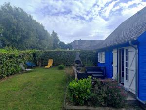 a blue house with a yard next to a hedge at La maison bleue in Saint-André-dʼHébertot