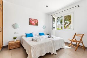 two beds in a white room with a window at Villa Verano in Cala Galdana +26 photos