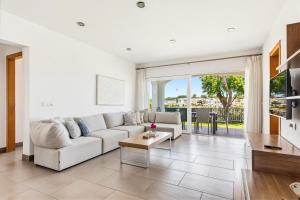 a white living room with a couch and a table at Villa Verano in Cala Galdana