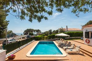 a swimming pool with lounge chairs and an umbrella at Villa Verano in Cala Galdana