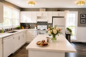 a kitchen with white cabinets and a bowl of food on a counter at Downtown Picton Retreat - Near Sandbanks and Wineries in Picton