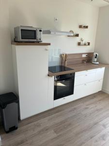 a kitchen with white cabinets and a microwave on a counter at La Bohème d'Opale in Boulogne-sur-Mer