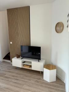 a living room with a tv on a white cabinet at La Bohème d'Opale in Boulogne-sur-Mer