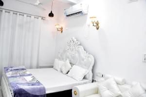 a white bedroom with a bed and a couch at Green Valley Resort in Dūngarpur