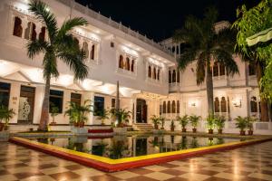 a building with a pool in front of it with palm trees at Green Valley Resort in Dūngarpur