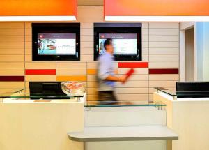 a man walking past a counter in a restaurant at ibis Lyon Est Beynost in Beynost