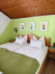 a bed with white sheets and pillows in a room at Blumenpension Strauss - Ferienwohnungen in Ossiach