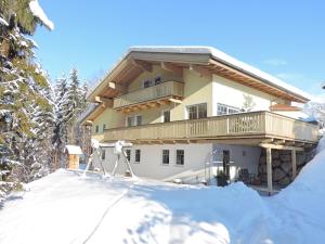 a house with a balcony in the snow at Appartement Auszeit in Saalfelden am Steinernen Meer