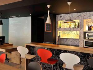 a restaurant with a bar with red and white chairs at ibis Lyon Centre in Lyon