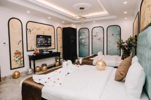 two beds in a room with paintings on the walls at Doris Luxury Hotel in Hanoi