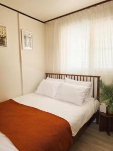 a bedroom with a bed with white pillows and a window at Jian Stay Bora in Sin'gal
