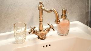 a sink with a bottle and glasses on it at Hiša 88 in Dutovlje +36 photos