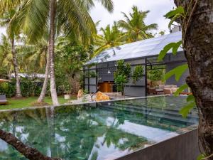 an infinity pool in front of a house with palm trees at BlackRoots Unawatuna in Unawatuna