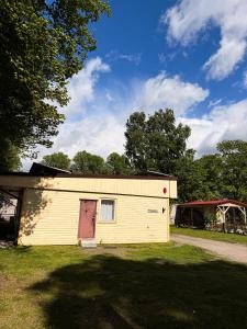 a yellow building with a red door in a yard at Sadama Hostel & Caravan Camping in Pärnu +21 photos
