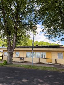 a yellow building with a tree and a street light at Sadama Hostel & Caravan Camping in Pärnu