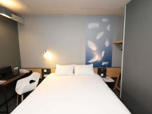 a bedroom with a large white bed and a desk at ibis Egletons in Égletons