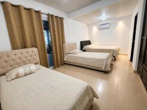 a hotel room with three beds and a window at Chitre Villa by Otium in Monagrillo