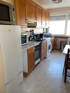 a kitchen with wooden cabinets and a white refrigerator at Appartement Mona Lisa in Ris-Orangis