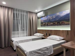 a room with two beds and a painting on the wall at GuestHouse-Medeu in Almaty