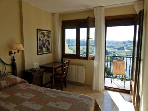 a bedroom with a bed and a desk and a window at El Mirador de Trasvia Comillas in Trasvia