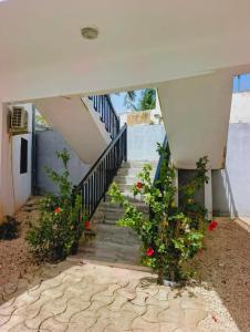a staircase leading up to a house with red flowers at Izuba chambres avec vue sur piscine in Ngaparou +2 photos