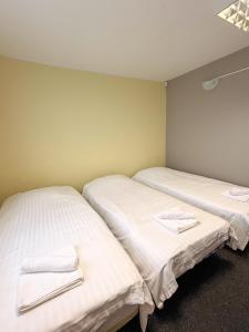 three beds in a room with white sheets and towels at Sadama Hostel & Caravan Camping in Pärnu