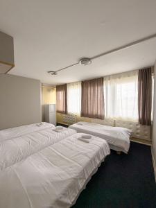 a hotel room with three beds and windows at Sadama Hostel & Caravan Camping in Pärnu
