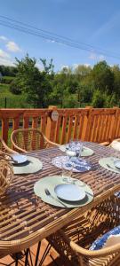 a wooden picnic table with plates and glasses on it at MAKS HOUSE KASZUBY Balia Lake and Forest Retreat in Przewóz