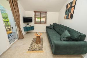 a living room with a green couch and a table at Green Oasis Residence in Radanovići