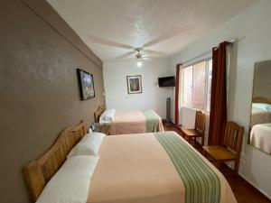 a hotel room with two beds and a window at Posada Temazcal Santo Domingo in Tepoztlán