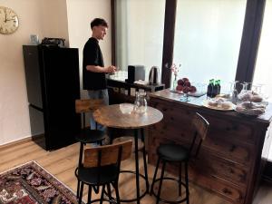 a man standing in a kitchen with a counter with stools at Pension Grum in Arnoldstein