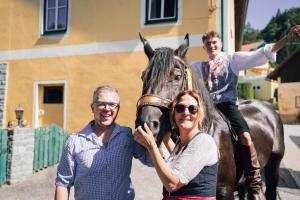 two men and a woman standing next to a horse at Pension Grum in Arnoldstein