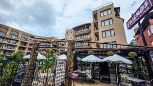 a building with tables and umbrellas in front of it at Friends Family Hotel in Sunny Beach