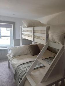 a bedroom with two bunk beds and a window at Hughie Toms Cottage in Greencastle