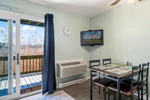 a dining room with a table and a television and a balcony at Assateague Inn 105-S in Deep Hole