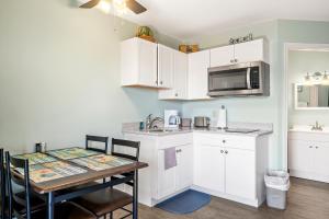 a kitchen with white cabinets and a table with a microwave at Assateague Inn 105-S in Deep Hole