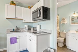 a kitchen with white cabinets and a microwave at Assateague Inn 105-S in Deep Hole
