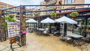 an outdoor restaurant with tables and chairs and umbrellas at Friends Family Hotel in Sunny Beach