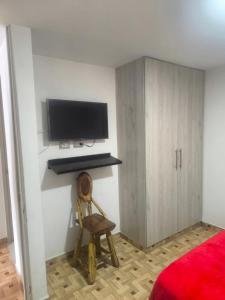 a bedroom with a tv and a chair and a cabinet at apartamento vacacional red 1 in Salento