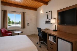 a hotel room with a bed and a desk with a television at Ramada by Wyndham 1000 Islands Gananoque in Gananoque