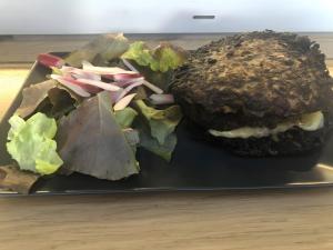 a black plate with a hamburger and lettuce at Yourte Volcans Puy de Dome in Montfermy +22 photos