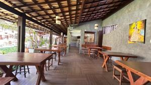 an empty restaurant with wooden tables and chairs at Pousada Saudosa Maloca in Arraial d'Ajuda