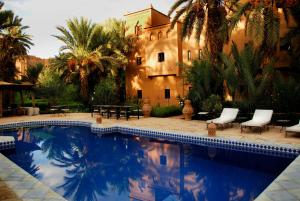a swimming pool in front of a house with palm trees at Maison d'Hôtes Kasbah Azul in Agdz