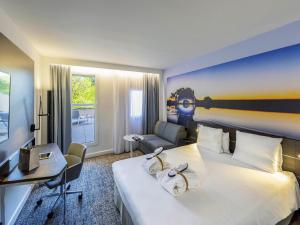 a hotel room with a large bed and a desk at Novotel Toulouse Centre Compans Caffarelli in Toulouse