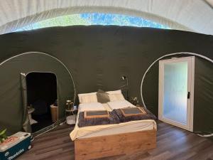 a bedroom with a bed in a green tent at Bubble Tent Altmühltal in Greding